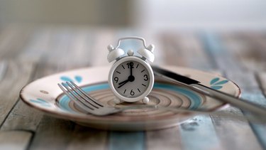 Close up view of alarm clock on a plate to symbolize intermittent fasting