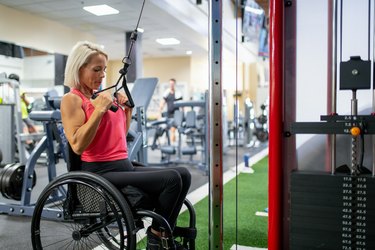 Person in wheelchair working upper-body muscles in a gym