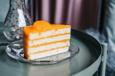 Visceral fat image of slice of orange layer cake on a glass plate on green table