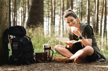 Female hiker during small halt eating sandwich in green forest