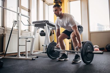 Person in the gym holding a barbell getting ready to do a deadlift