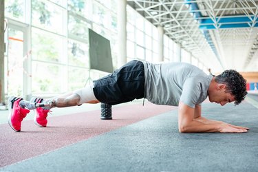 Person with prosthetic leg doing a forearm plank to demonstrate exercises to help you target lower belly fat