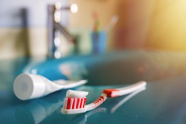 Teeth health: brush and toothpaste on blue sink in bathroom.
