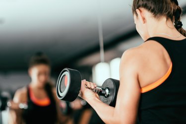 Person exercising with dumbbells in front of the mirror
