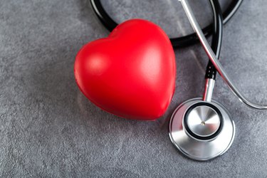 Stethoscope and red heart on a stone table. Cardiology concept