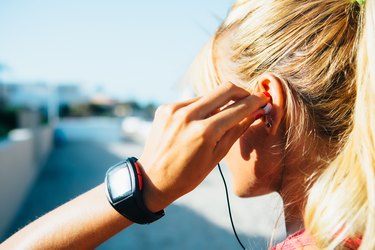 woman putting on headphones before her outdoor workout