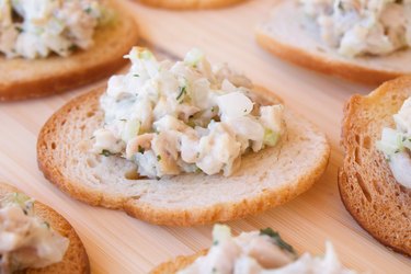Chicken Salad on crackers on wooden table.