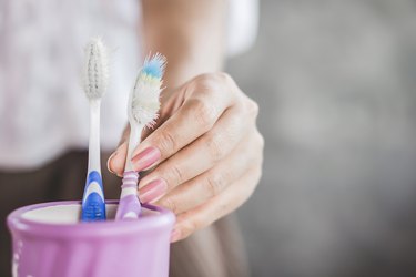 close view of a woman's hand using an old toothbrush