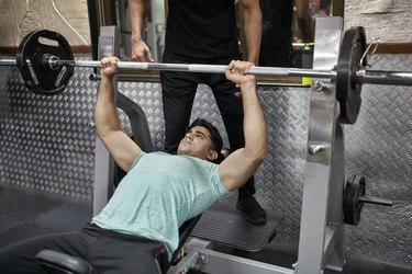 Person in gym performing an incline bench press to build upper-body strength..