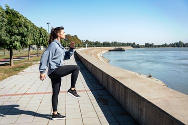 Person wearing gray sweatshirt and black leggings running in place outside.