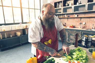 Happy male chef preparing healthy salad