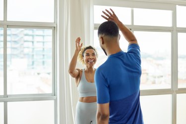 Personal trainer and client high-fiving after a workout to demonstrate a successful New Year's resolution.