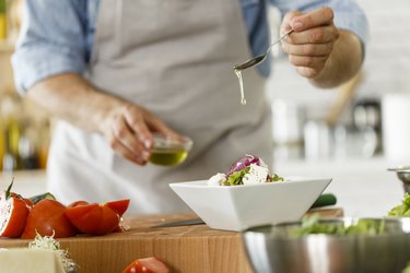 Man pouring olive oil on salad, as an example of daily habits for healthy aging