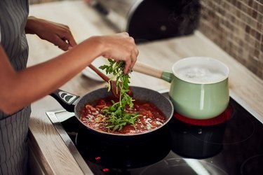 女人在不锈钢偷金属锅烹饪番茄酱