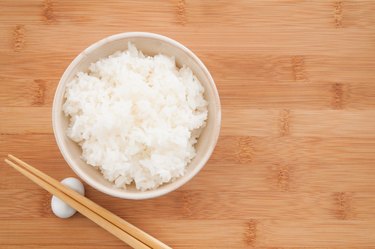 Cooked white Nishiki rice on a wooden table with chopsticks