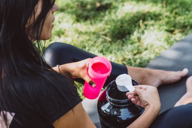 woman athlete prepares a protein shake in a shaker after training outdoors. Sports nutrition. Soft selective focus.