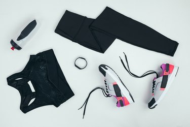 overhead shot of workout gear, including black leggings, sports bra, sneakers, water bottle and smartwatch