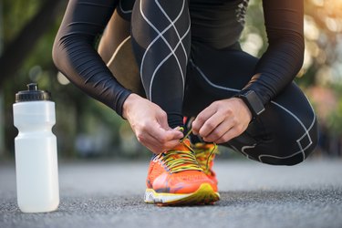 Close-up of running shoes, water bottle and smartwatch as the best gifts for runners.