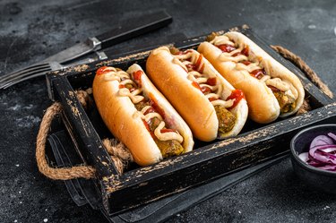 Broiled hot dogs with with assorted toppings and meatless Vegetarian sausage. Black background. Top view