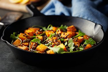 roasted butternut squash with green lentils and arugula in a cast iron pan
