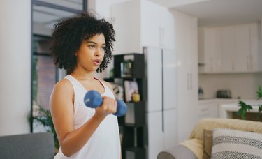 Person performing a dumbbell curl in living room.