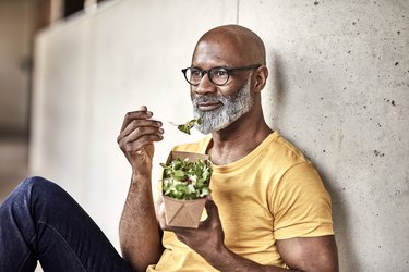 Man having lunch break eating a salad with nitrate-rich leafy greens for muscle building