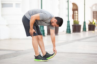 Fit man doing a toe touch stretch before exercise outside