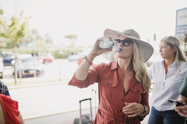woman drinking bottled water while traveling, to prevent traveler's diarrhea