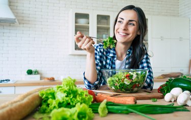 女人坐在厨房里吃着一大份沙拉，作为治疗胃灼热的自然疗法