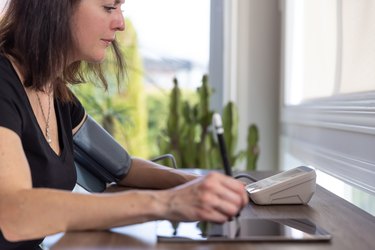 Adult Woman checking blood pressure on Auto blood pressure Machine at home