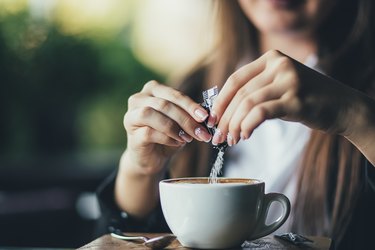 添加糖的妇女在桌上的新鲜的芳香咖啡，特写镜头