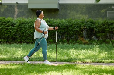 Woman in Leggings and a Tank Top Doing Nordic Walking With Trekking Poles After Appendicitis