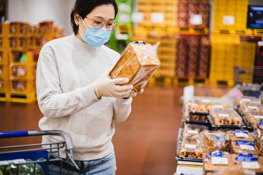 Woman wearing a face mask shopping for whole grain bread in the grocery store