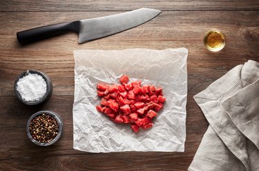 Chopped raw veal meat cubes for meat stew on white cooking paper and wooden table