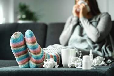 一名病的女人在沙发上吹鼻子，想知道她是否感冒了。流感