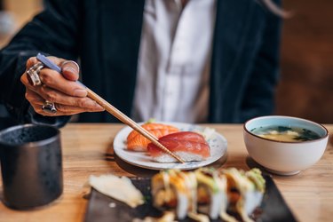 Man's hand showing man eating sushi in sushi bar