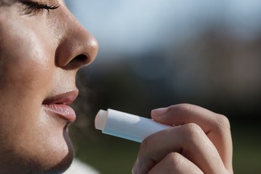 Close side view of a person applying lip balm with SPF to their lips in the sunshine