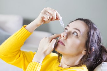 Closeup view of young woman applying eye drops, as a home remedy to get rid of pink eye