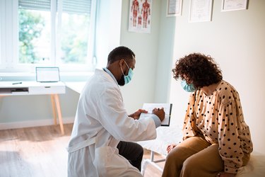 Female patient explaining her symptoms to a doctor, as an example of what to do when your doctor doesn't listen