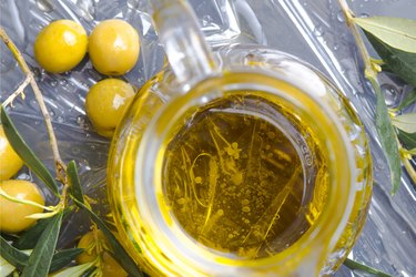 overhead shot of jar of extra virgin olive oil with olives