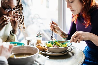 three adults eating lunch together in a sunny cafe