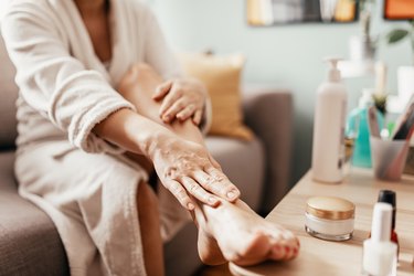 Woman moisturizing her feet, as an example of one reason athlete's foot is not healing