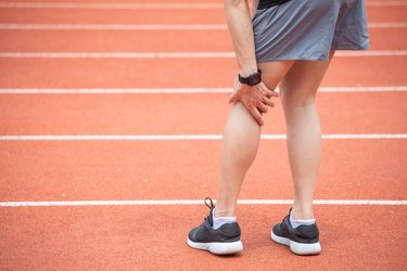 Close up of runner woman holding her leg, suffuring from ITB Syndrome.