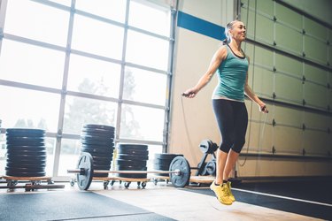 Person in workout clothes jumping rope in gym, demonstrating how to jump rope.