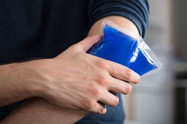 Person Applying Ice Gel Pack On An Injured Elbow