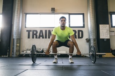 fit man doing a barbell deadlift variation at the gym