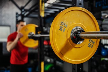 man setting up barbell in a power rack, avoiding the barbell mistake of not using weight clips