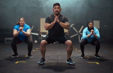 a group of people doing squats to illustrate the question should females train differently than males