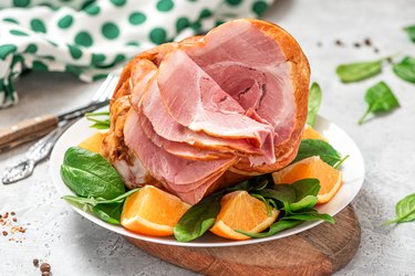 Sliced Kretschmar ham in a plate with spinach and oranges