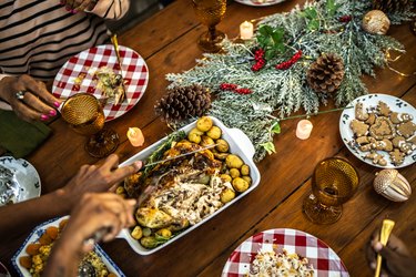 Top view of hands cutting turkey on a wood table decorated for the holidays to illustrate why ground turkey gives me gas and upsets my stomach